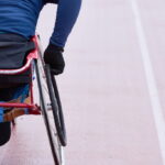 Rückansicht auf Rolli-Athlet auf der Tartanbahn.