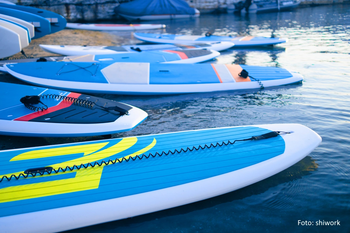 Mehrere am Strand aufgereihte SUPs