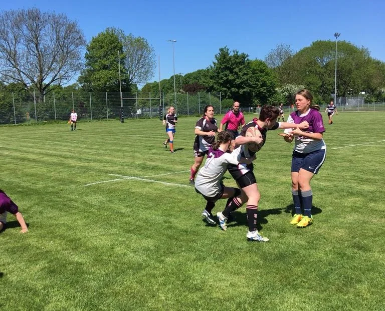 Anna Vierling rechts im lila-weißen Trikot unterstützt ihre Kieler Mitspielerin im Tackling. Foto: Rebecca Schütte