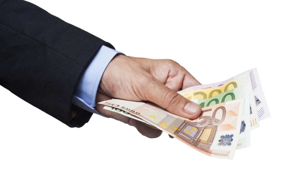 Männerhand überreicht eine Anzahl von Eurobanknoten | Geldübergabe