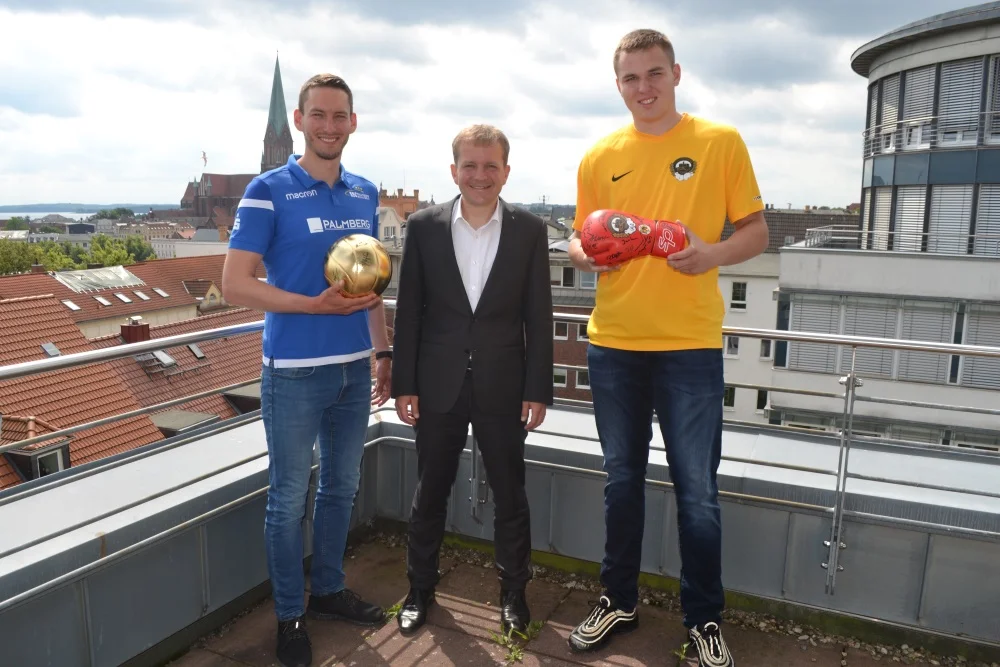 Heimspieltagskoordinator Peter Niepagen vom SSC Palmberg Schwerin (links) und Vize-Europameister Victor Jurk (rechts) vom BC Traktor Schwerin e. V. rufen gemeinsam mit Oberbürgermeister Rico Badenschier dazu auf, attraktive Gebote abzugeben, um den Nachwuchssport des TSV Schwerin zu unterstützen. Foto: © LHS Schwerin / Mareike Diestel