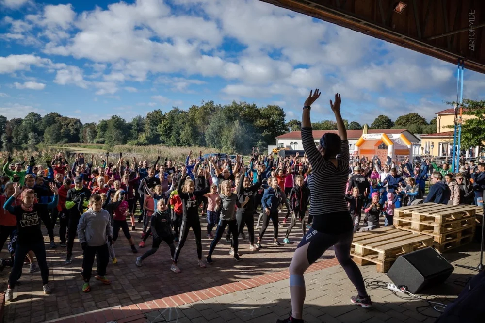 Loui heizt der Menge beim gemeinsamen Erwärmen ordentlich ein. Foto: FEEL THE RUN FEEL THE RUN - Der etwas andere Hindernislauf am 28. September 2019 IN Gützkow - Loui heizt der Menge beim gemeinsamen Erwärmen ordentlich ein