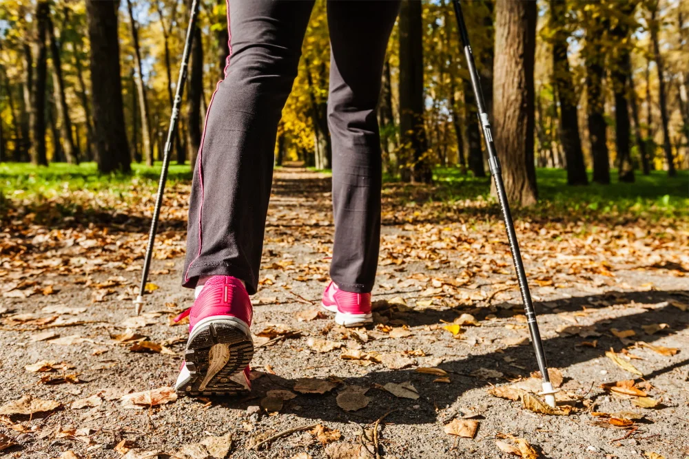 Nordic Walking: Frau wandert durch einen Park
