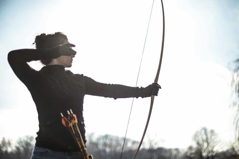 Junge Frau hält Jagdbogen in der Hand und trainiert in der Natur | Stockfoto: envato elements