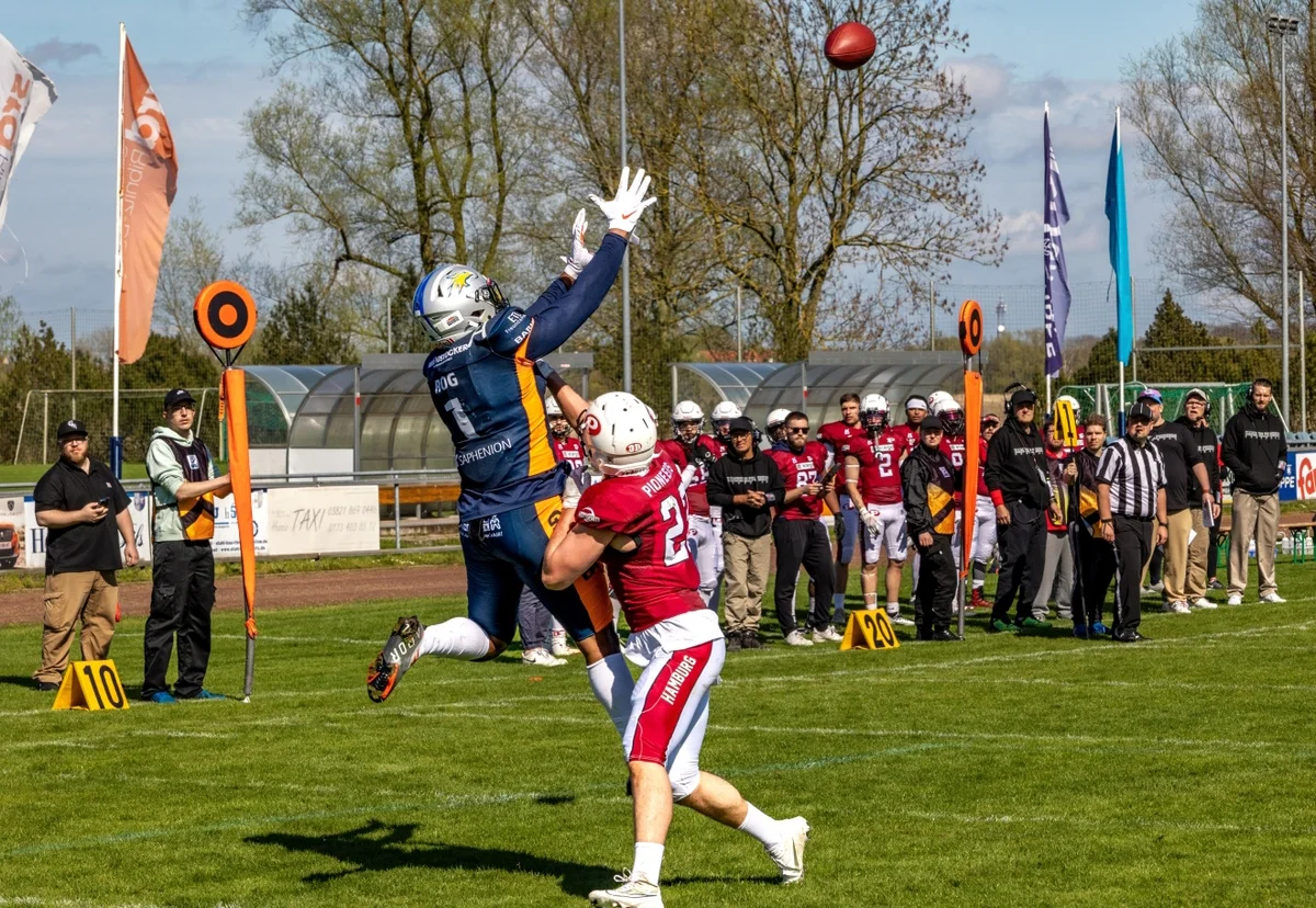 Ein Rostocker Footballspieler springt in die Luft um den Ball zu fangen. Ein gegnerischer Spieler versucht dies zu verhindern