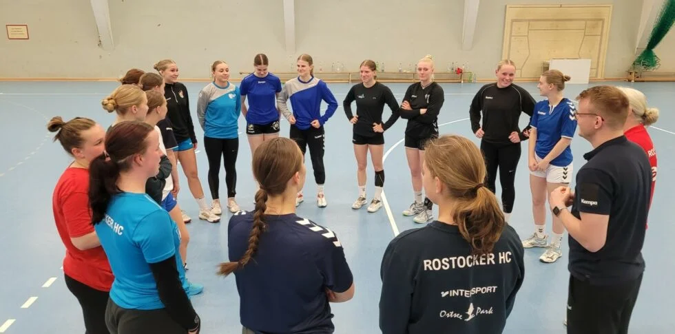 Junge Handballerinnen sind für eine Besprechung im Kreis versammelt.