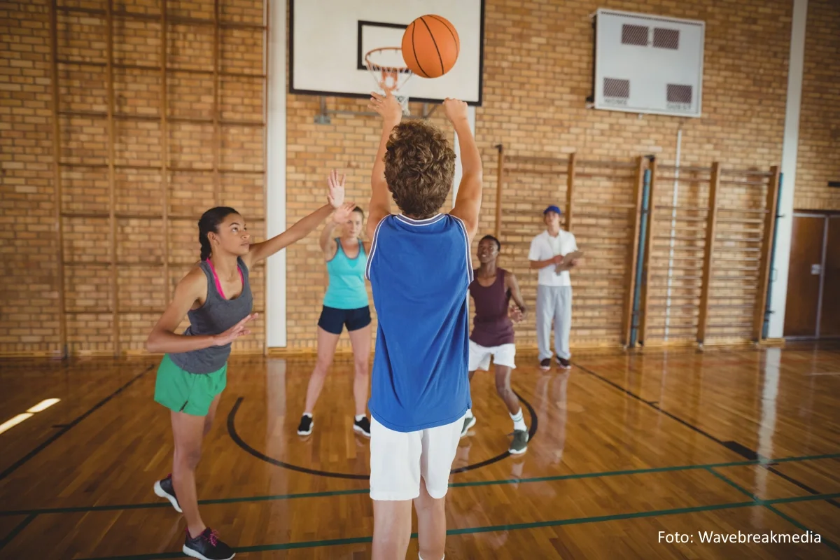 Basketball spielende Kinder in einer Sporthalle