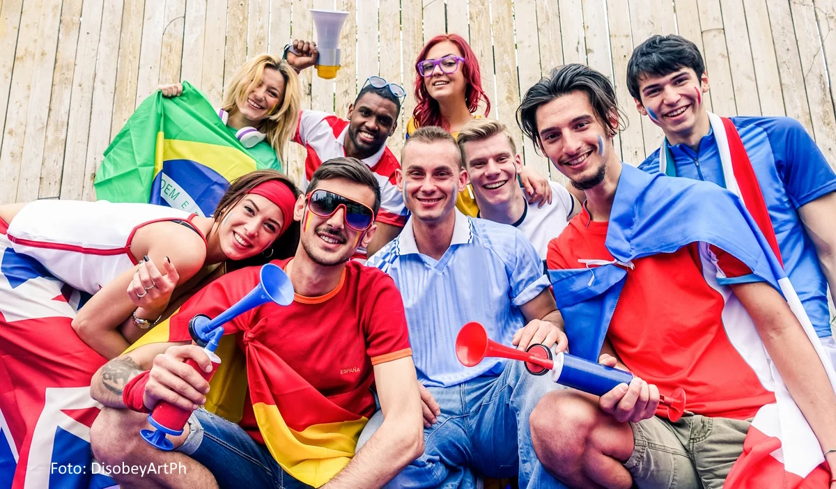 Eine Gruppe junger Leute aus unterschiedlichen Nationen feiert ein Sportevent.