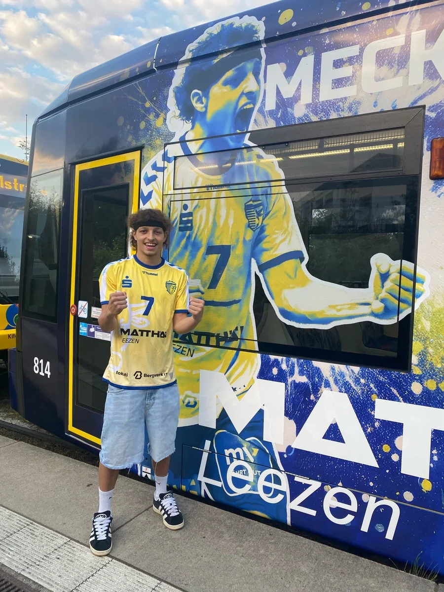 Schweriner Handballspieler vor der neu im Stiere-Stil beklebten Straßenbahn.