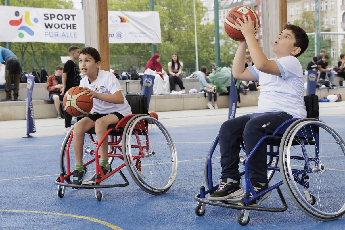 Zwei Jungen im Rollstuhl spielen anlässlich der "SportWoche für Alle" Basketball.
