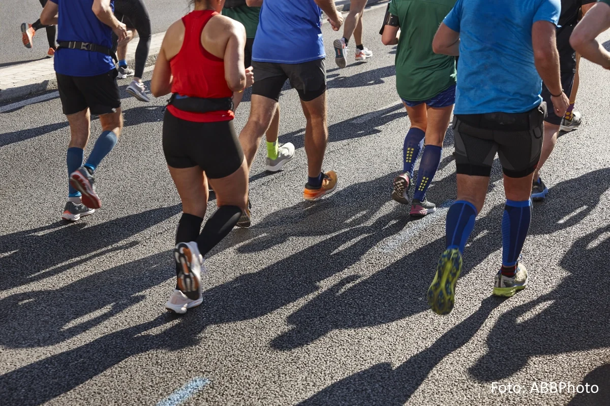 Eine Gruppe von Sportler:innen (Schulter abwärts im Bild) während eines Straßenlaufs