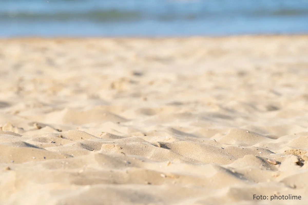 Sandstrand mit Wasser im Hintergrund