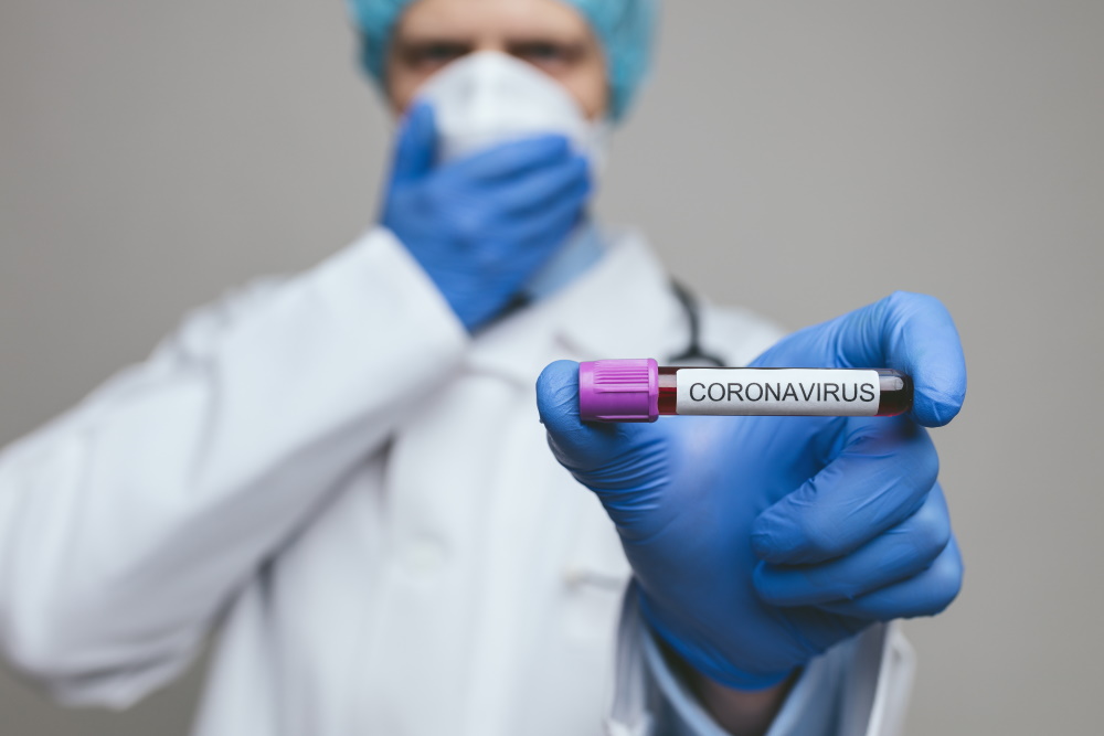 Symbolbild: Mediziner mit Reagenzglas und Aufschrift Coronavirus