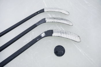 Eishockey: Puck und Hockeyschläger liegen auf der Eisfläche