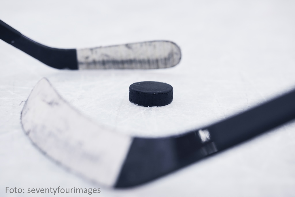 Eishockeyschläger und Puck auf Eisfläche