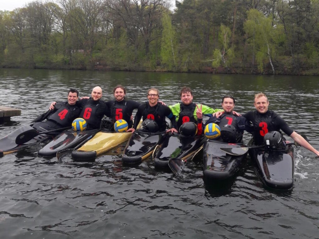 Arm in Arm und in ihren Kanus sitzend - Das 7-köpfige Kanupolo-Team aus Rostock und Potsdam
