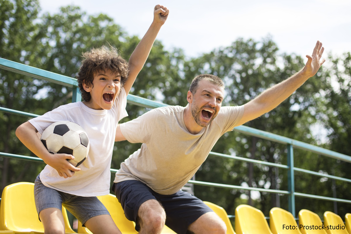 Sportfamilie (Vater und Sohn) feuern auf der Tribüne ihre Mannschaft an