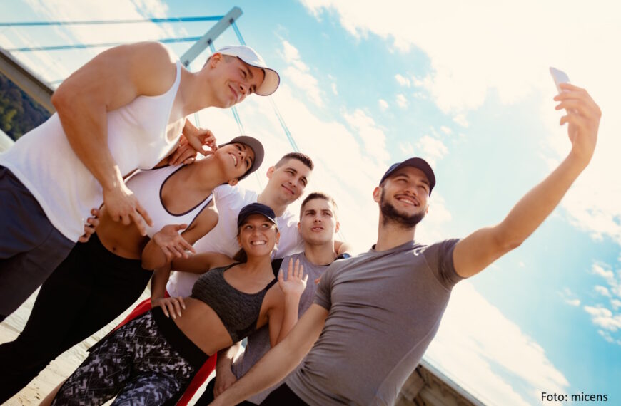 Gruppe aus 6 Jugendlichen/jungen Erwachsenen macht am Strand ein Selfie