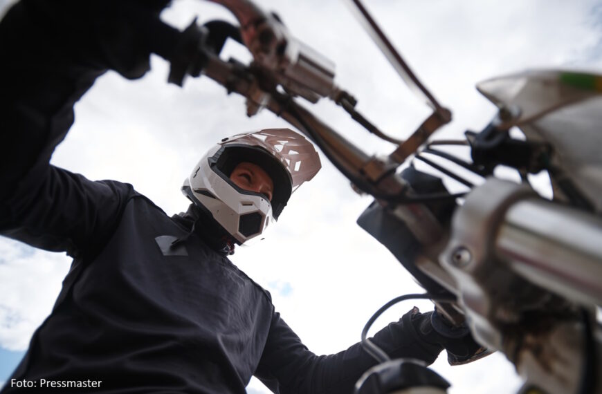 Mottorradfahrer mit schwarzer Kleidung und weißem Helm aus der Froschperspektive