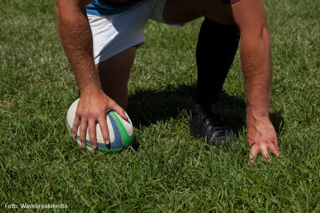 Knieender Rugbyspieler auf dem Rasen