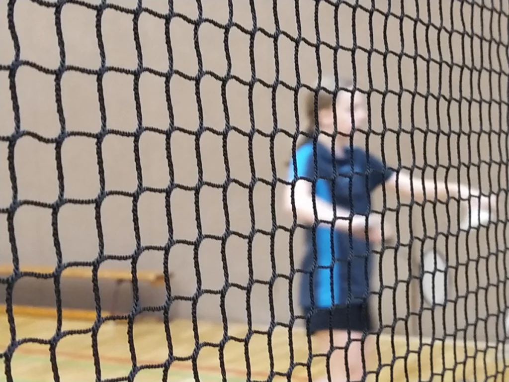 Badmintonnetz mit Spielerin im Hintergrund