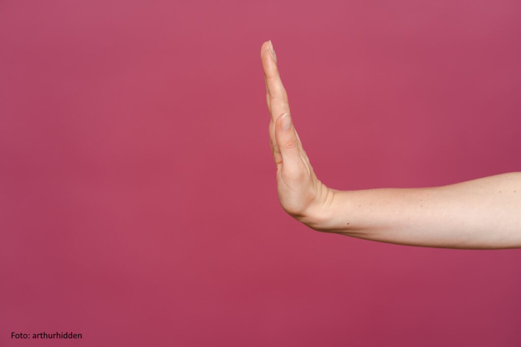 "Stop" gestikulierende weibliche Hand auf rosafarbenem Hintergrund