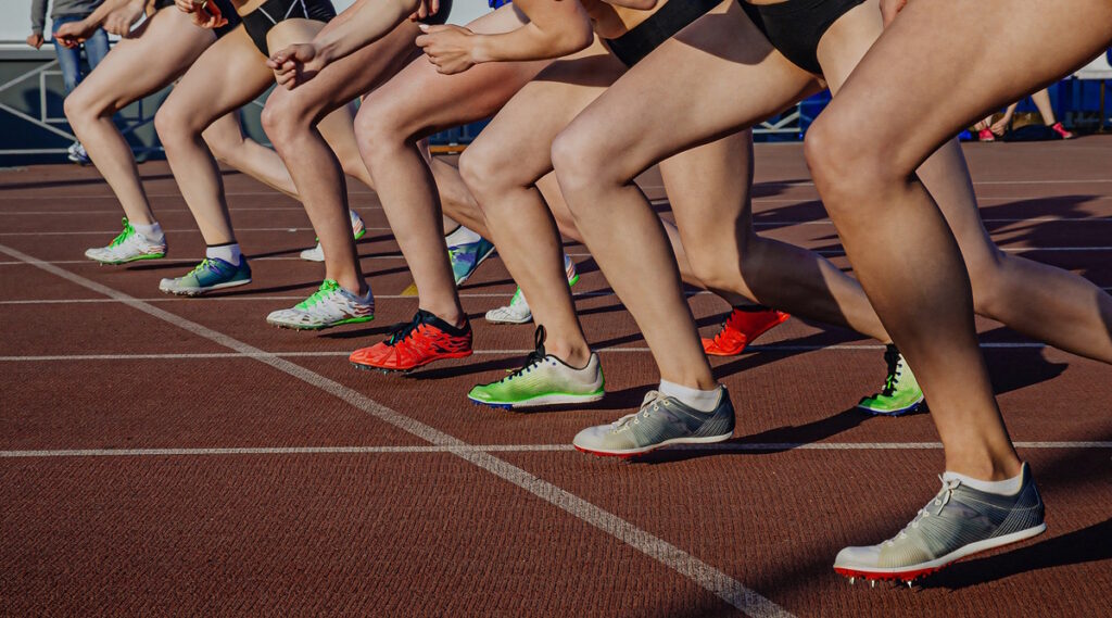 Sportlerinnen in Laufschuhen mit Spikes an der Startlinie der Mitteldistanz