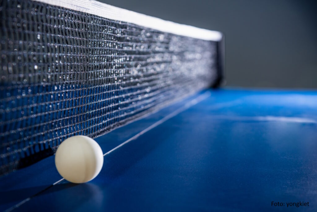 Nahansicht: Blaue Tischtennis-Platte mit Ball und Netz