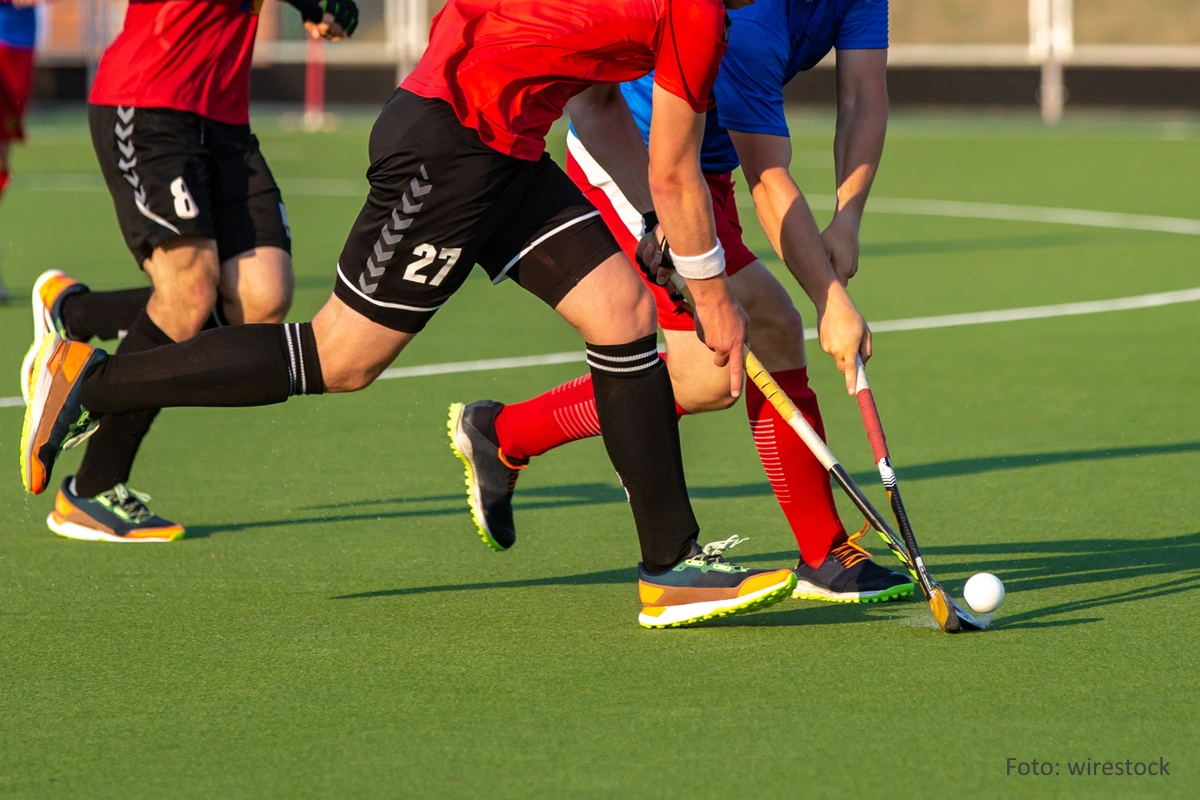 Nahaufnahme der Unterkörper mehrerer aktiver Feldhockeyspieler auf Kunstrasen