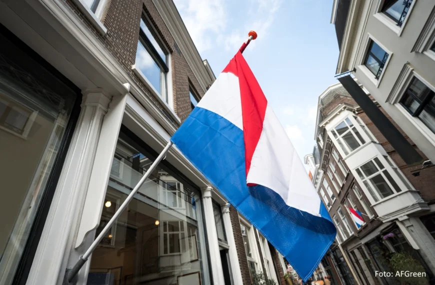 Eine niederländische Flagge weht in einer Häusergasse neben einem Schaufenster.