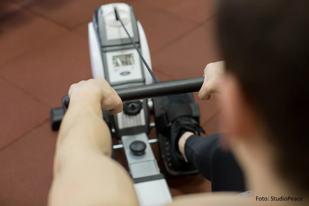 Blick über die Schulter eines Athleten der an einem Ergometer trainiert.