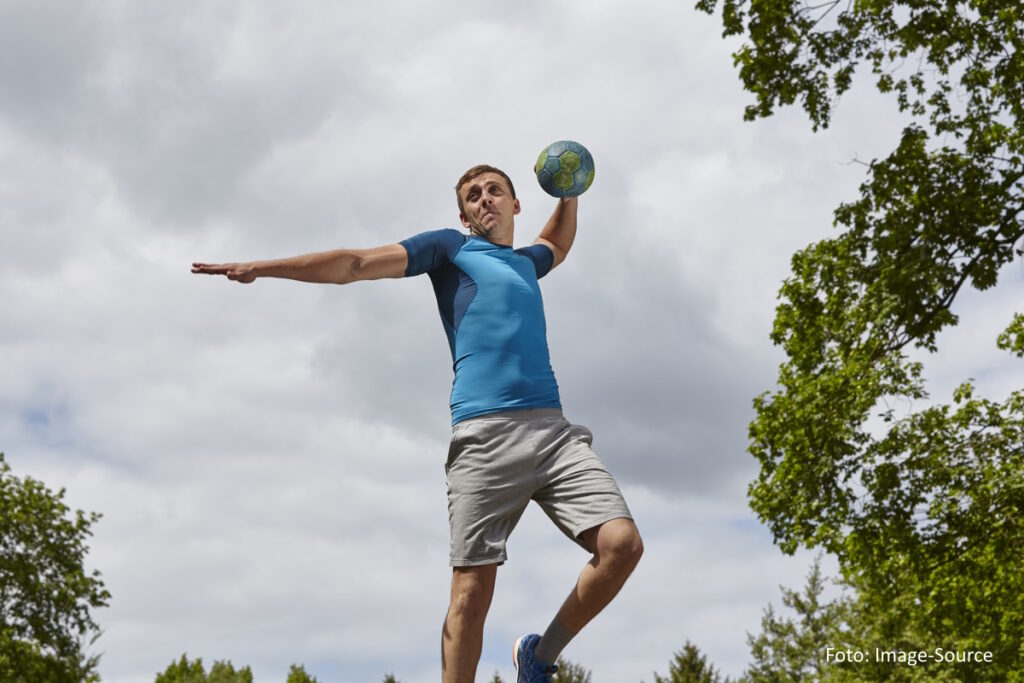 Junger männlicher Ballsportler bereitet sich auf den Ballwurf auf einer Outdoor-Anlage vor.