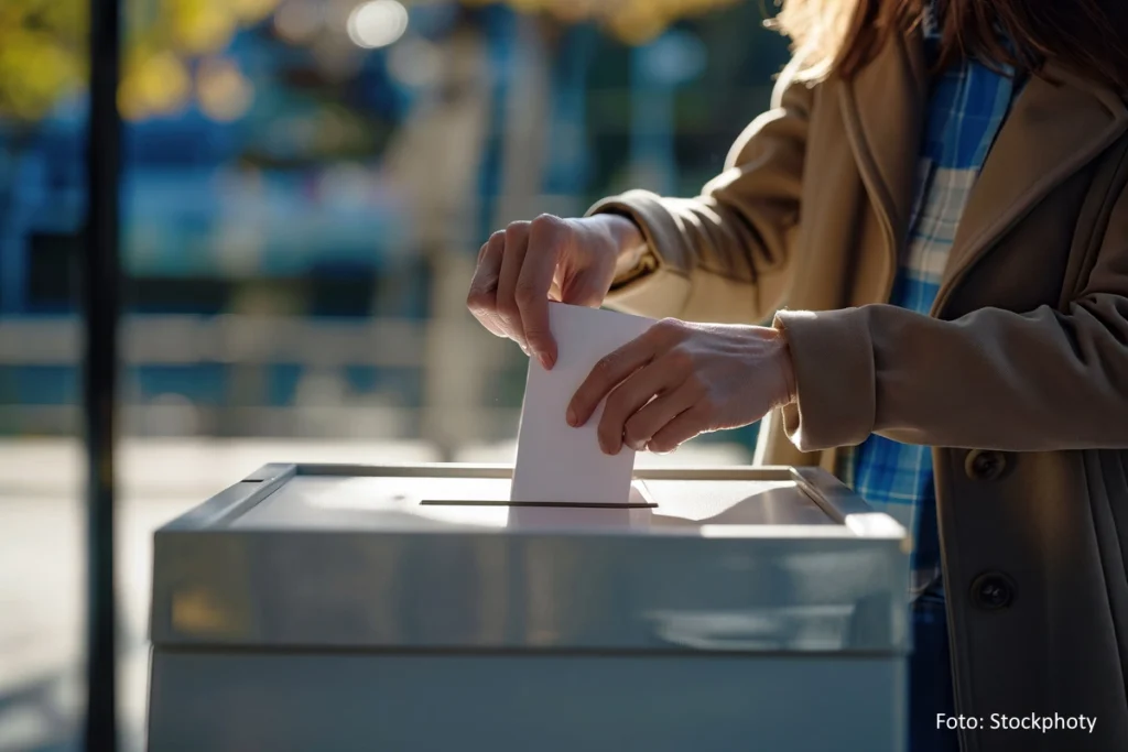 Eine Frau steckt einen Stimmzettel in die Wahlurne