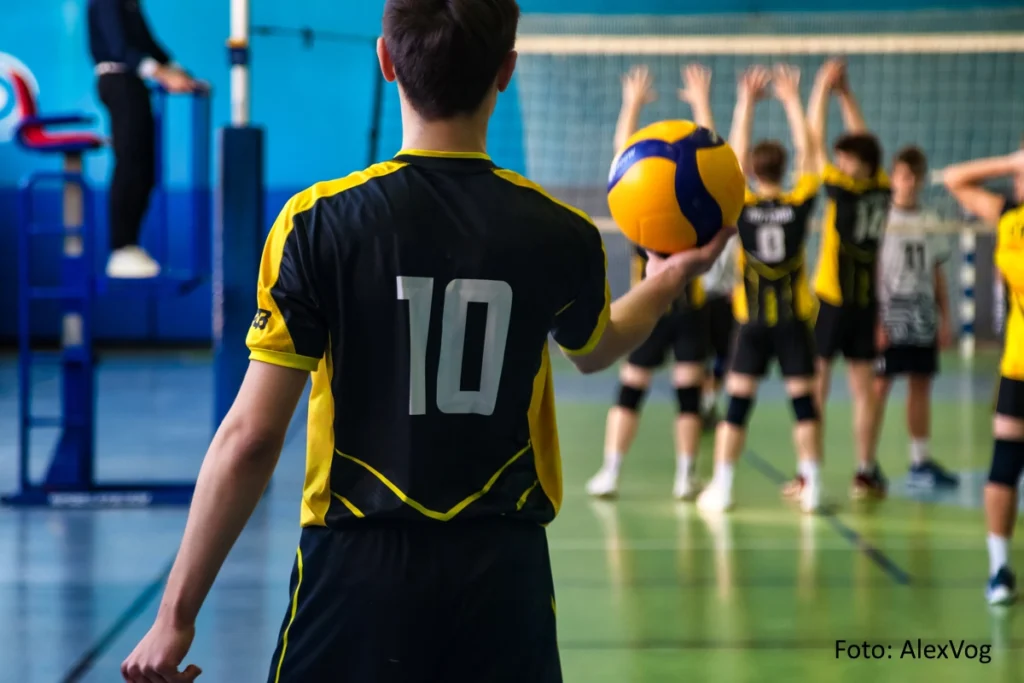 Rückansicht eines Volleyballspielers in schwarz-gelber Sportbekleidung mit der Nummer 10 beim Aufschlag