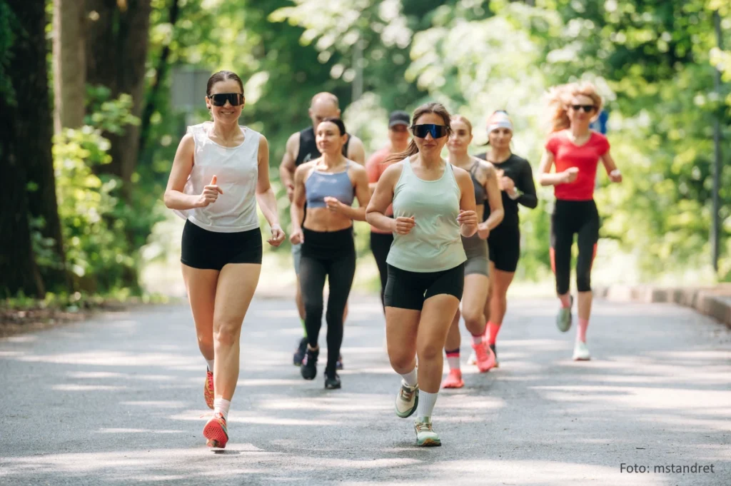 Gruppe sportlicher Menschen nimmt an einem breitensportlichen Waldlauf teil.
