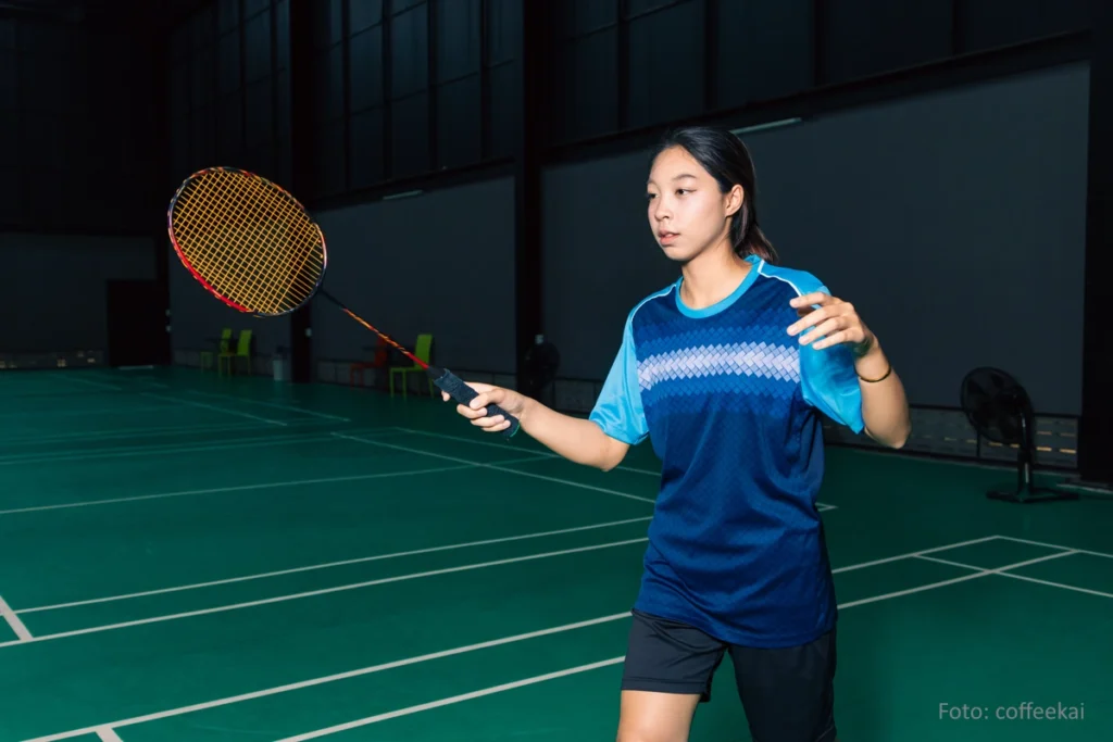 Junge Badmintonspielerin auf einem professionellen Court.