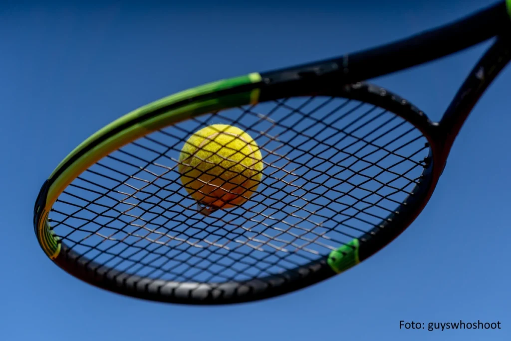 Tennisschläger und Tennisball vor blauem Hintergrund
